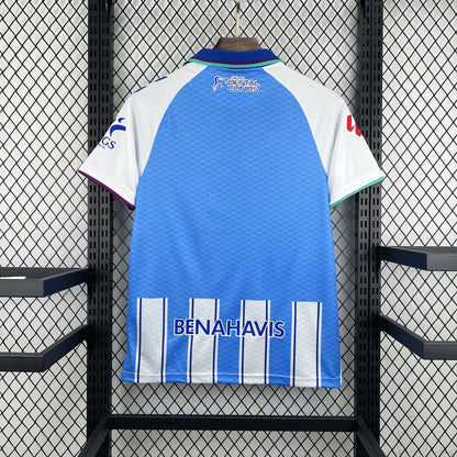 Close-up of the Málaga crest on the 2026/27 home jersey