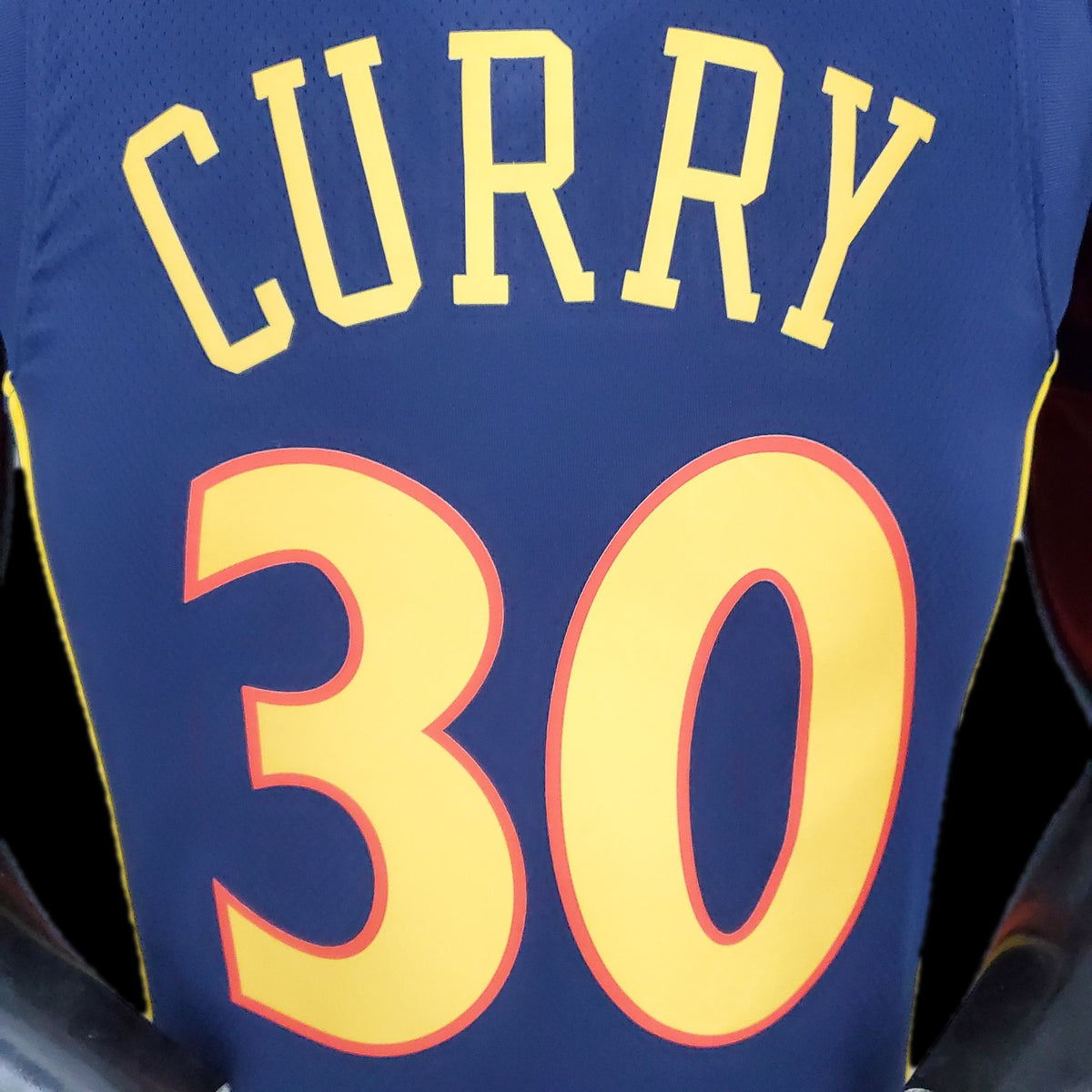 Gold Warriors lettering and number 30 outlined in orange on navy jersey
